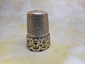 A silver thimble with a raised decorative border. c1870
