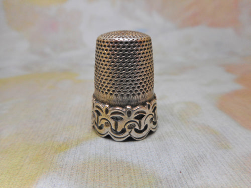 A silver thimble with a raised decorative border. c1870