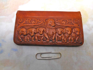 A charming tan leather stamp / card case embossed with a row of dogs