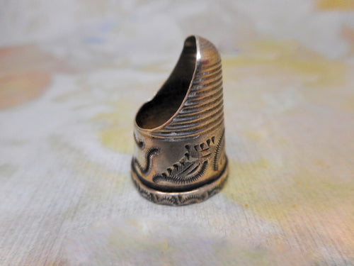 An engraved silver finger guard / thimble. Mid 19th century.
