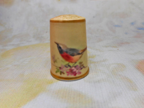 A blush ivory Worcester porcelain thimble painted with a bird. c1870.