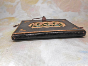 A tooled leather needle case with petit point panels. c 1860.