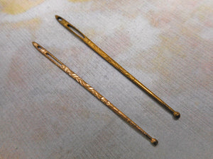 Two decorative gilt metal bodkins. c 1900