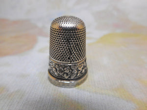 A silver thimble embossed with a band of flowers. c 1835 s/d