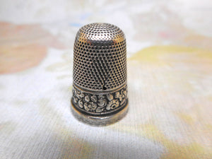 A silver thimble embossed with a band of flowers. c 1835 s/d