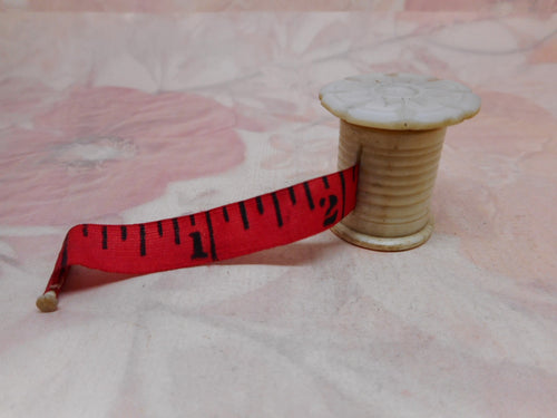 An antique mother of pearl topped tape measure from a Victorian sewing box.