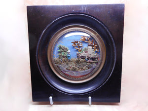 A small, framed miniature diorama of figures in a landscape.