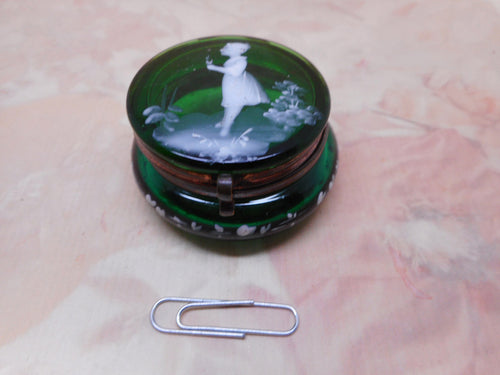 A green glass jar decorated with a Mary Gregory style girl.