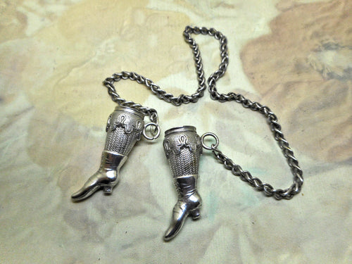 A pair of silver knitting needle ends -lady's stockinged legs. Late 19thc