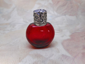 A small ruby glass scent / salts bottle with an embossed silver lid.  19thc