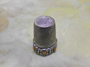 A German silver thimble with coral coloured beading. Late 19th century.