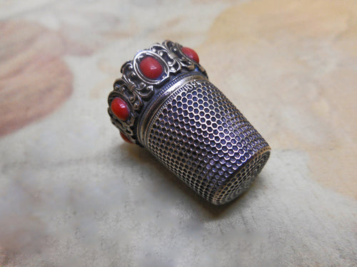 An antique silver thimble with coral beading. Late 19thc