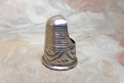 A silver finger guard which is a type of thimble dated 1906